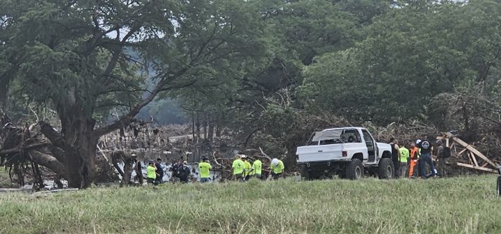 Crews and trucks line up along a riverbank