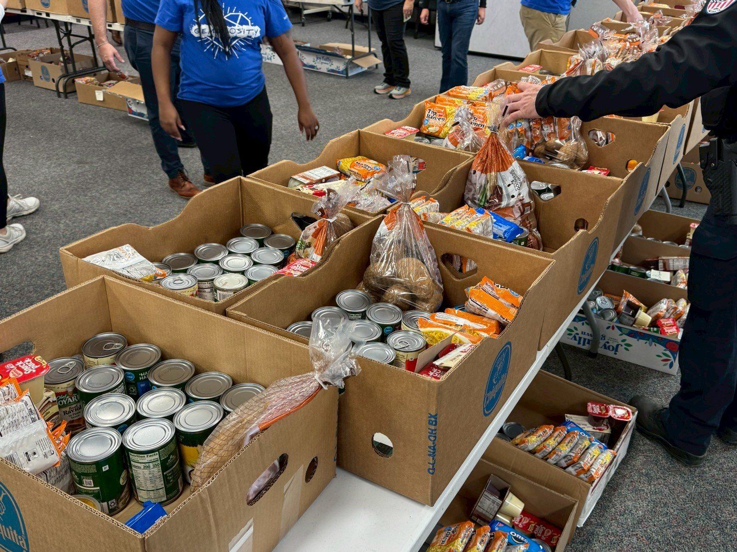 Volunteers pack boxes of canned goods, bread, potatoes and snacks for families in need
